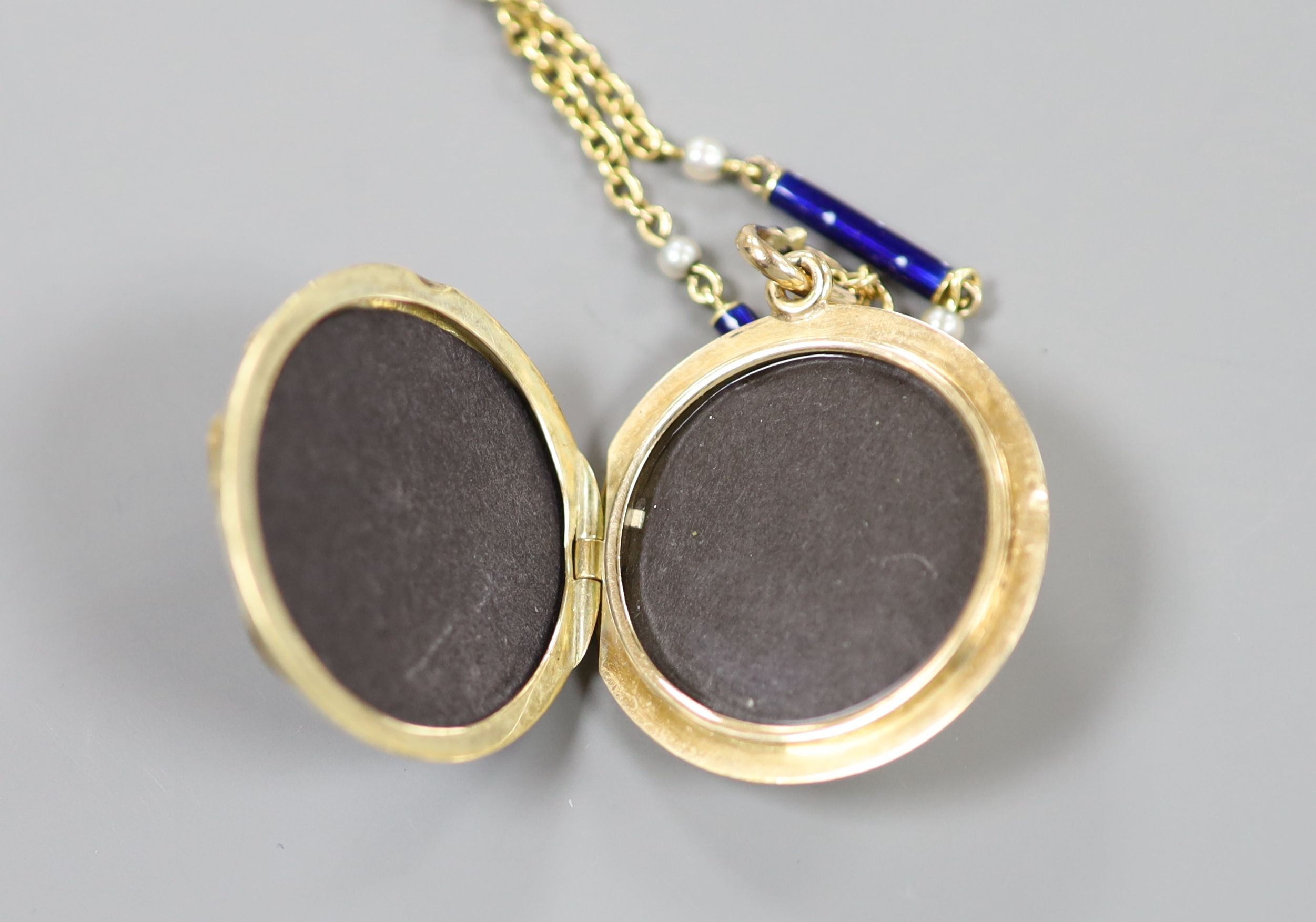 A yellow metal, blue enamel and rose cut diamond set monogrammed circular locket (a.f.) 29mm, on a 9k, seed pearl and blue enamel baton link chain, 48cm